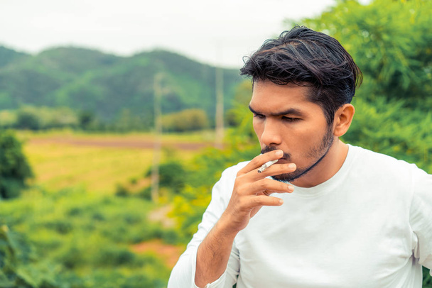 Νέος άνθρωπος κάπνισμα τσιγάρων στην ύπαιθρο. - Φωτογραφία, εικόνα