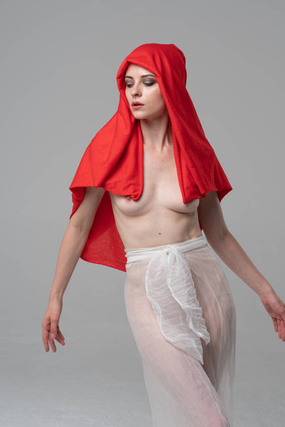 young beautiful girl posing in the studio, standing in white transparent clothes and a red scarf - Photo, Image