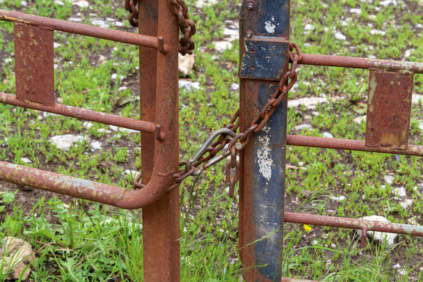 Σκουριασμένες μεταλλικές πύλες δεμένες με μεταλλική αλυσίδα - Φωτογραφία, εικόνα