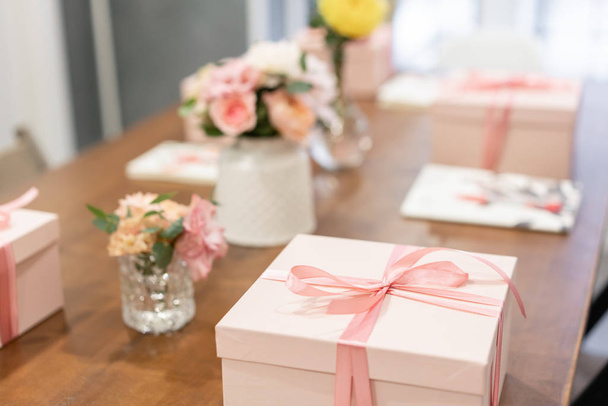 Gift box tied with ribbon on wooden table. Lifestyle. Education in the school of floristry. Master class on making bouquets. Summer bouquet. - Photo, Image