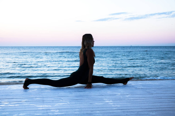 mulher sênior irreconhecível fazendo ioga ao nascer do sol no mar, silhueta de poses de ioga
 - Foto, Imagem