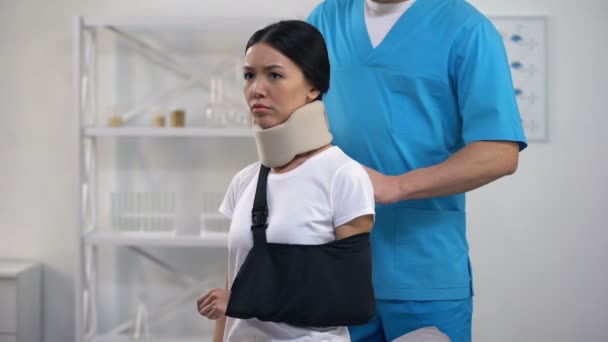 Professional male surgeon fixing arm sling upset patient in foam cervical collar - Video