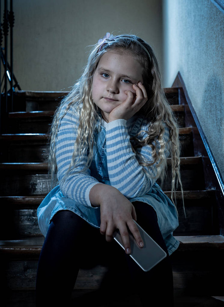 Sad depressed girl Bullied by text message humiliated online social media by classmates. Sad depressed young girl victim of cyberbullying by mobile phone sitting on stairs feeling lonely hopeless. - Valokuva, kuva