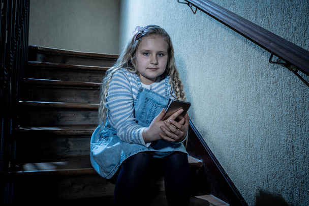 Sad depressed girl Bullied by text message humiliated online social media by classmates. Sad depressed young girl victim of cyberbullying by mobile phone sitting on stairs feeling lonely hopeless. - Zdjęcie, obraz