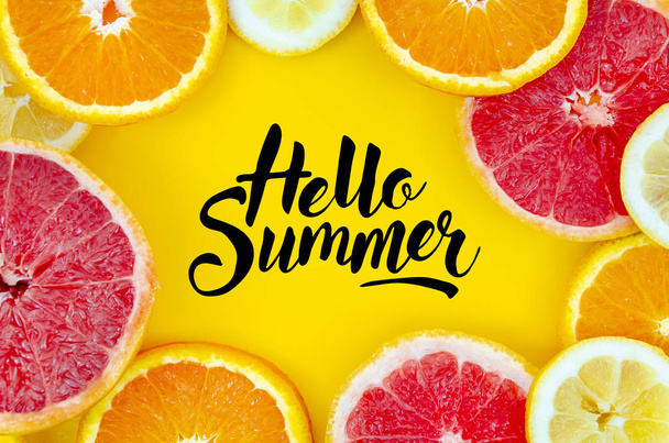 Hello summer sign with citrus fruits. Flat lay oranges, grapefruits and lemons slices. Over yellow background - Photo, Image