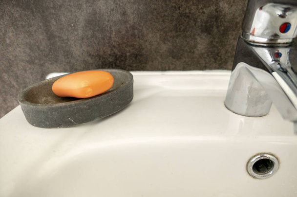 orange soap against grey background at the sink in the bath - Photo, Image