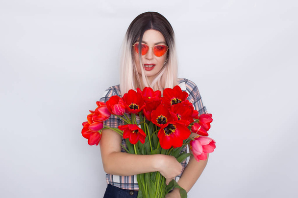 Blonde woman holding bouquet of red tulips - 写真・画像