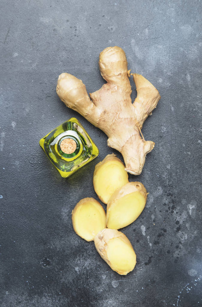 Ginger oil and fresh ginger root, gray kitchen table, copy space, top view - Φωτογραφία, εικόνα