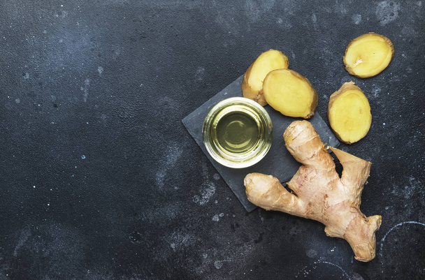 Ginger oil and fresh ginger root, gray kitchen table, copy space, top view - Фото, зображення