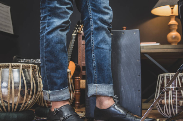 Стильний музикант в джинсових і подвійне монах взуття грає Cajon, Перуанський барабан використовується зазвичай з Стерилізень фламенко Dance.  - Фото, зображення