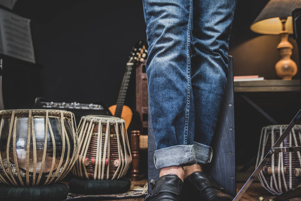A stylish musician in denim and double monk shoes plays the Cajon, a Peruvian drum used commonly with Spains Flamenco dance.  - Foto, immagini