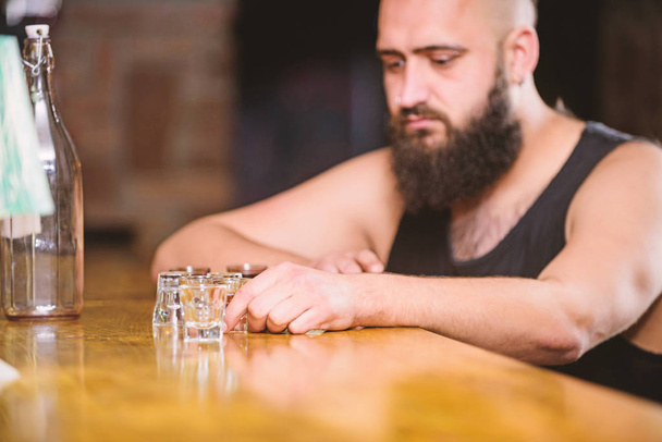 Hipster brutal man drinking alcohol ordering more drinks at bar counter. Alcoholism and depression. Guy spend leisure in bar with alcohol. Man drunk sit alone in pub. Alcohol addicted concept - Foto, Imagen