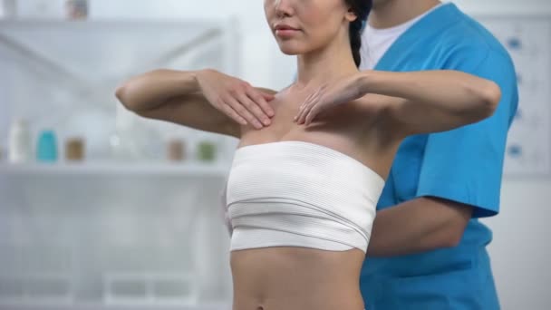 Professional plastic surgeon wrapping chest compression female patient, health - Imágenes, Vídeo