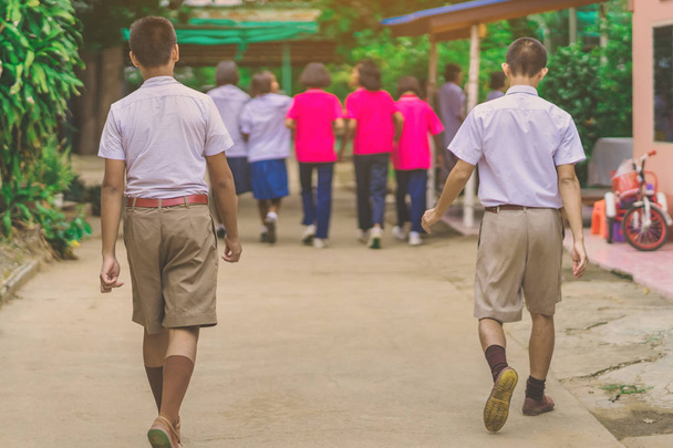 Šťastný mužský student chodí za svými přítelkyněmi ve škole. - Fotografie, Obrázek
