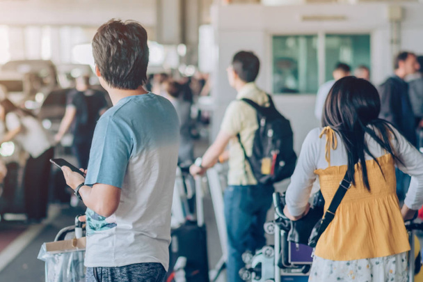 Los pasajeros con gran soporte de equipaje de rodillos para esperar a que el coche para recoger en la terminal de llegada del aeropuerto
. - Foto, Imagen