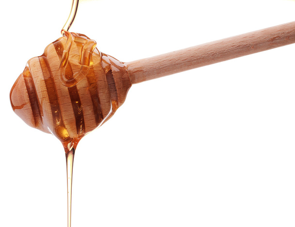 Honey dripping from a wooden honey dipper isolated on white back - Foto, Imagem