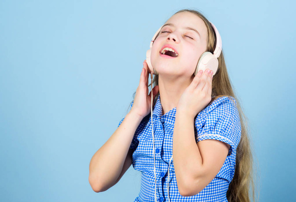 Music is what her feelings sound like. Small child enjoy electronic sound playing in earphones. Little girl relaxing with melodious sound. Cute kid listening to sound track in headphones, copy space - Valokuva, kuva