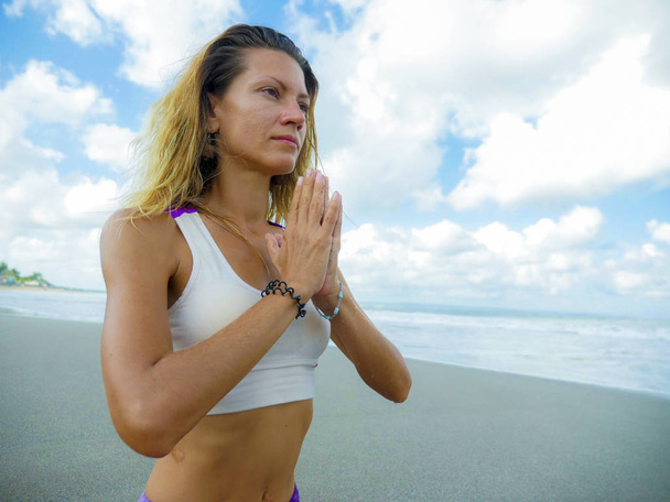 fiatal boldog és vonzó fitt és sovány szőke nő csinál jóga és pihenés gyakorlat szabadban gyönyörű strandon pihenés és meditáció gyakorlat - Fotó, kép
