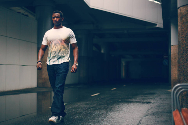 Black guy in a white T-shirt in a dark tunnel - Photo, Image