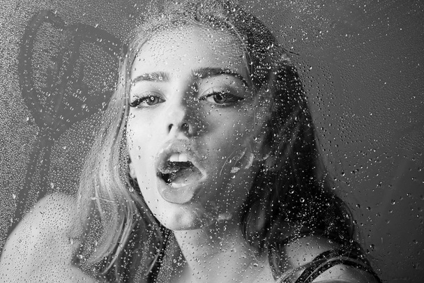 Fashion beauty and love. Window with water drops before girl with makeup. Shower and hygiene spa treatment. Rain drops on window glass in heart shape. Sexy woman behind plastic sheet with water drops - Photo, Image
