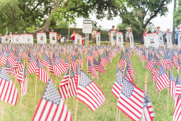 Banderas americanas de césped con fila borrosa de personas llevan desfile de pancartas de soldados caídos
 - Foto, Imagen