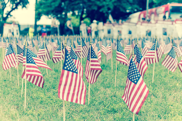 Imagen filtrada césped banderas estadounidenses con fila borrosa de personas llevan desfile de pancartas soldados caídos
 - Foto, imagen