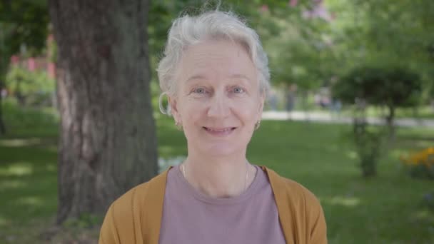 Different emotions of old woman with grey hair in the beautiful park. Adorable mature grandmother resting on a sunny warm spring day outdoors. - Video