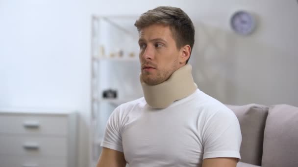 Sad male in foam cervical collar hardly breathing, feeling upset after trauma - Filmagem, Vídeo