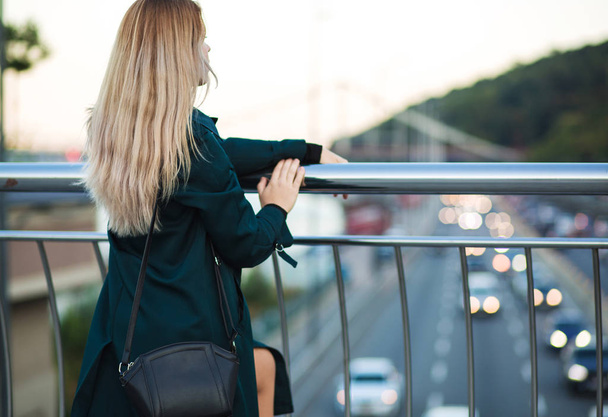 Pretty young woman wearing green coat and holding purse posing a - Photo, Image