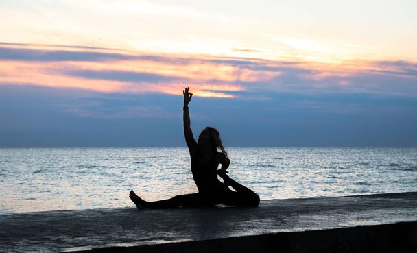 невпізнавана сенаторка з красивим тілом робить йогу розколотою на сході сонця на морі, силует пози йоги
 - Фото, зображення