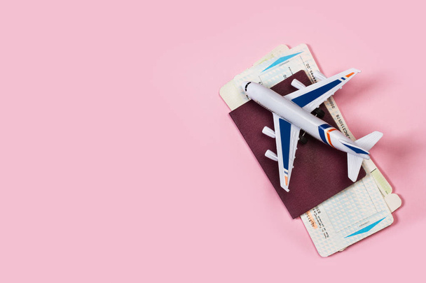 ein Spielzeugflugzeug mit Pass und Bordkarte auf rosa Hintergrund - Foto, Bild