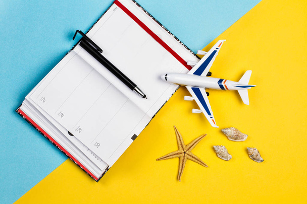 Un avión de juguete con un diario sobre un fondo amarillo y azul claro
 - Foto, Imagen