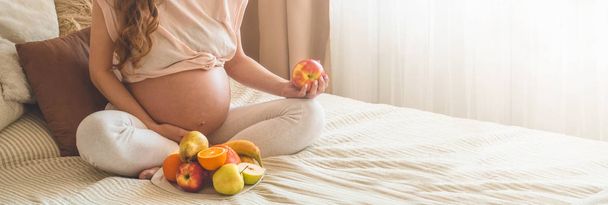 Zwangerschap en gezonde biologische voeding. Zwangerschap en grapefruit. Zwangere vrouw genieten van vers fruit in bed, vrije ruimte. - Foto, afbeelding