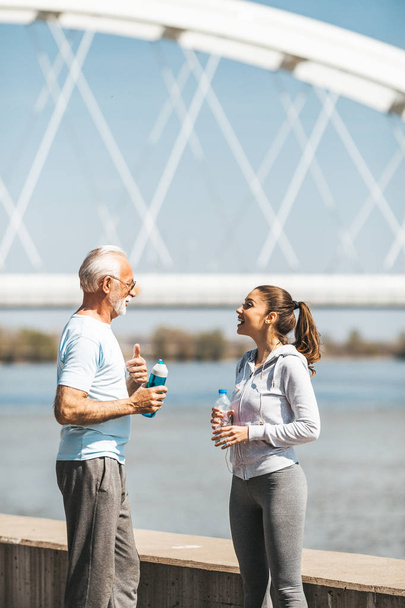 Fit senior man in good shape jogging and exercising together with his young adult daughter coach or instructor. - Foto, imagen