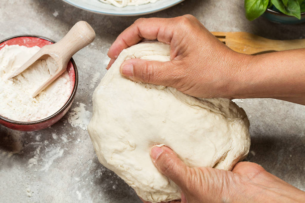 Woman kneading dough on a wooden table - Фото, зображення