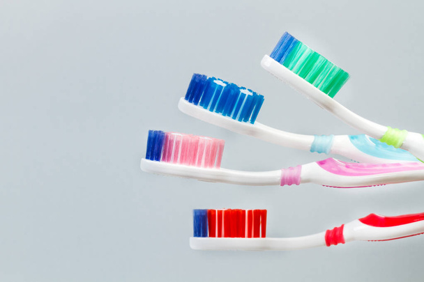 Quattro spazzolini da denti colorati in plastica su sfondo grigio
 - Foto, immagini