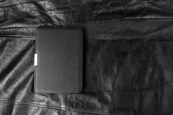 Electronic book in the case on black leather background - Fotografie, Obrázek