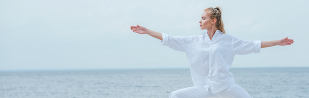 plan panoramique de fille attrayante pratiquant le yoga et debout avec les mains tendues
 - Photo, image