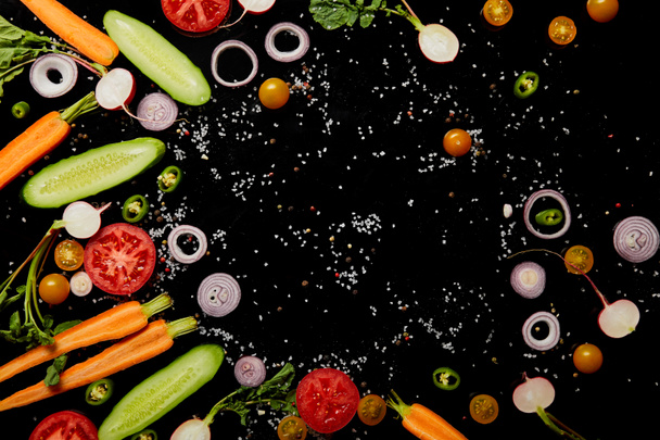 top view of fresh cut vegetables with salt isolated on black with copy space - Zdjęcie, obraz