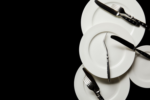 top view of white round plates with cutlery isolated on black with copy space - Fotoğraf, Görsel