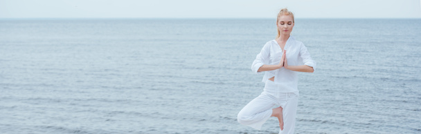 plan panoramique de jeune femme blonde aux yeux fermés pratiquant le yoga
  - Photo, image