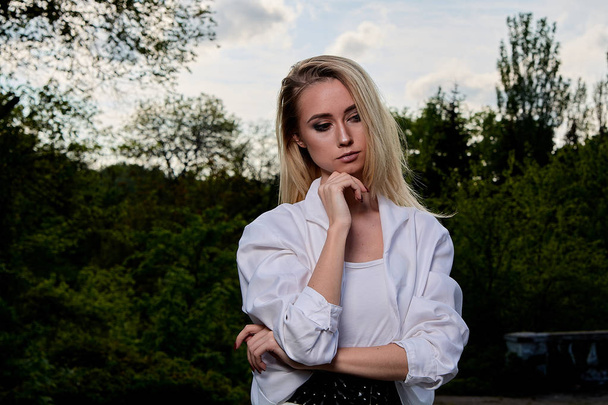 Blonde woman in the old sunny summer city park. Young woman modern portrait. - Photo, Image