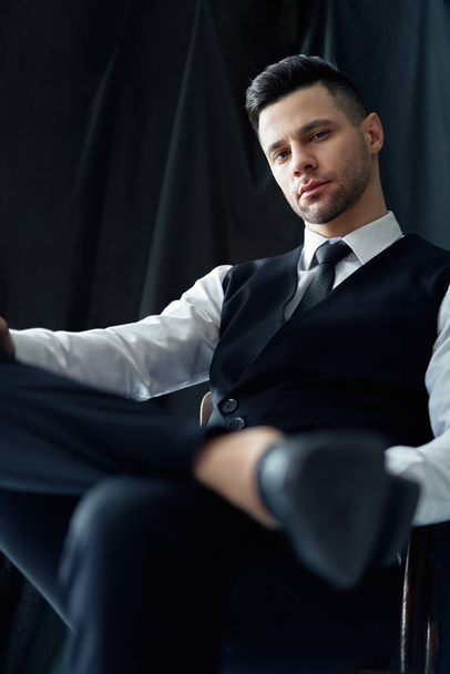 Confident handsome man in elegant suit posing sitting in chair. retro style       - Photo, image