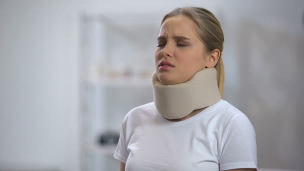 Young woman in foam cervical collar feeling sharp pain in neck, trauma result - Video