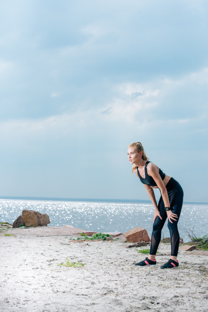 tired sportive young woman standing on beach near sea  - Fotografie, Obrázek