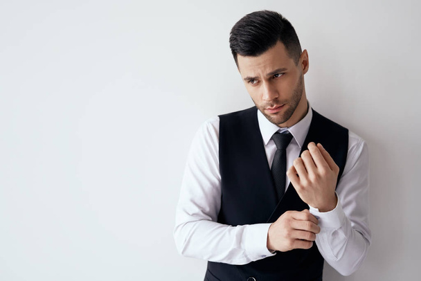 Handsome young man adjusting his sleeves and fixing his cufflinks against white background with copy space                                - Фото, изображение