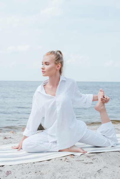 belle femme blonde étirant sur tapis de yoga près de la mer
  - Photo, image