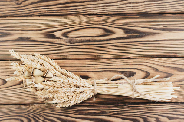One bundle of wheat and poppy tied up of brown rope on old rustic wooden planks - Photo, Image