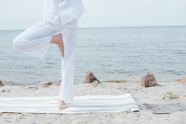 vue recadrée de jeune femme faisant du yoga près de la mer
  - Photo, image
