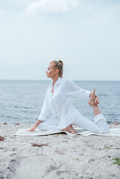 boční pohled na blonďatou mladou ženu, která cvičila jóga u řeky  - Fotografie, Obrázek
